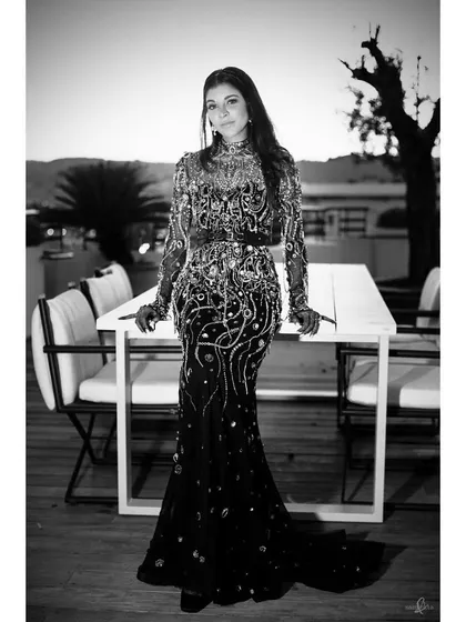 A black and white portrait of the bride, Shrutika, on her wedding day. Without color, the focus shifts to her intricate gown, her pose, and the elegant setting.