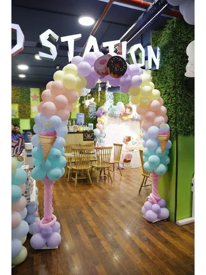 A wide shot of the incredible Candyland theme decor, with a balloon arch, custom backdrop, and sweet treat props.