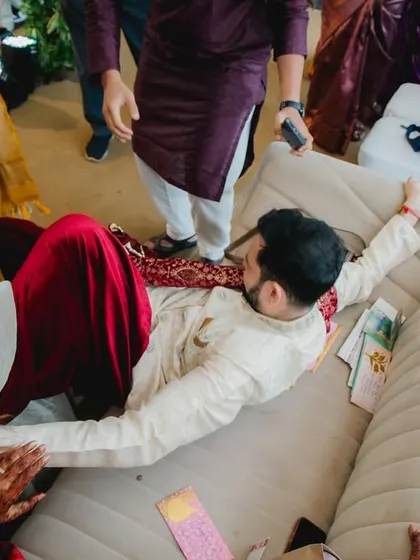 The groom, defeated but smiling, lies on the couch after the Joota Chupai ordeal. It's a candid moment of playful surrender that tells a great story.