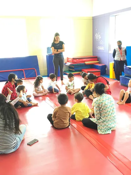 A group of children and parents sit together for a story or instructions, showing how our camps and classes foster a strong community feel.
