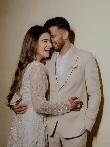 A candid moment of laughter and love between the couple, dressed in elegant white outfits for a pre-wedding event.