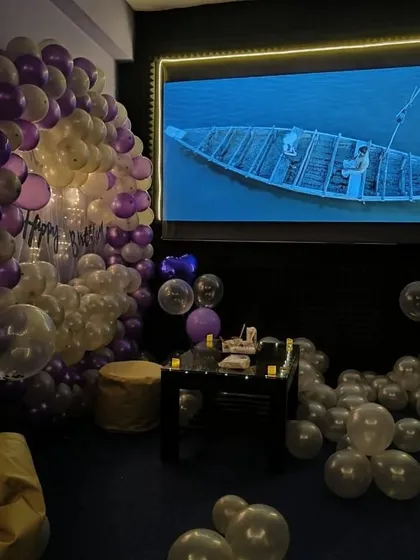 A serene moment during a birthday movie night, with the room decorated in shades of purple and white.