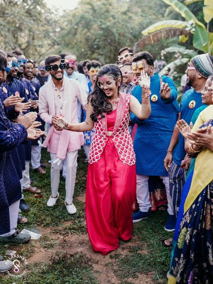 The couple's joyful entrance, surrounded by friends and family at their outdoor Haldi party.