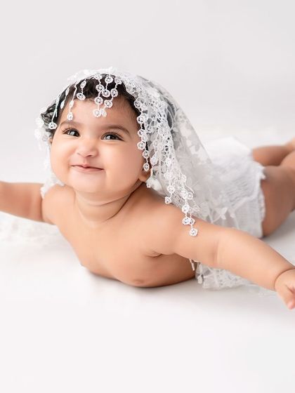 A playful baby portrait with a delicate lace veil.