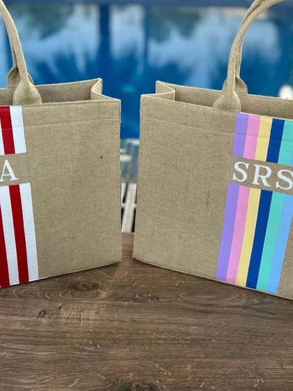 Two of our striped jute tote bags, one with red and white stripes and the other with pastel rainbow stripes. They are perfect for a beach day or grocery run.