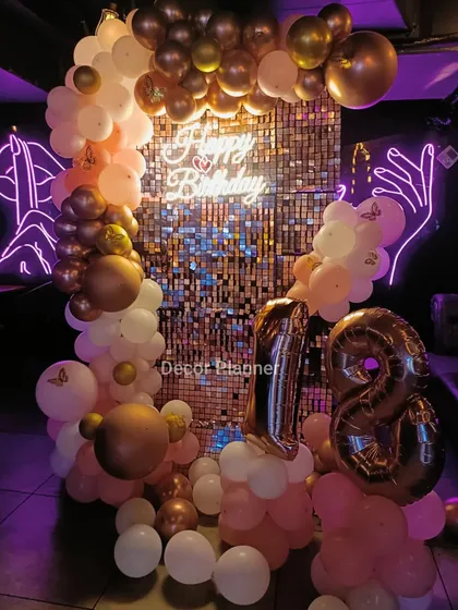 An 18th birthday deserves all the sparkle. This setup features a stunning rose gold sequin backdrop, a custom 'Happy Birthday' neon sign, and a beautiful balloon arch. The marquee numbers for '18' make it the perfect spot for celebrating this major milestone.