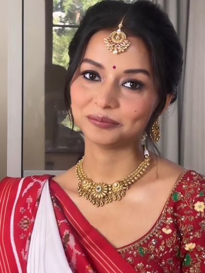 A frontal view of the classic bridal look. The hair is pulled back neatly into a bun, which keeps the focus on her beautiful features, traditional jewelry, and the auspicious bindi.