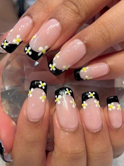 A Pinterest-inspired design brought to life. This creative take on a French manicure features a black tip adorned with sweet, hand-painted daisies.