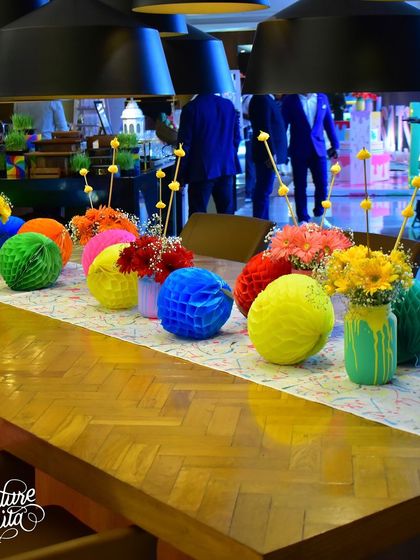 The dining table for the art party, featuring a paint-splatter runner and creative, colourful centrepieces.