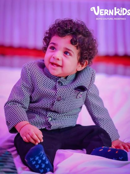 Another sweet shot of our little client in his printed jacket, looking happy and stylish under the festive lights.