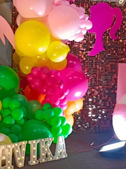 A close-up of the marquee letters for a Barbie-themed party, with colorful balloon clusters in the background.