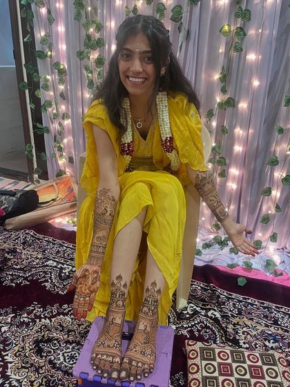 A happy bride showing off her complete bridal mehendi. The design flows from her arms down to her feet, creating a breathtaking look.