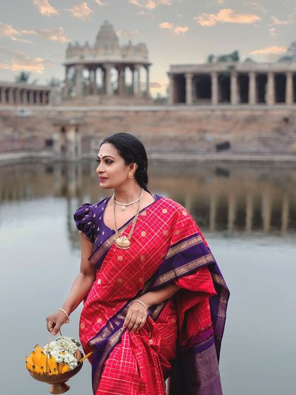 A spiritual sanctuary. The model, holding a basket of flowers, stands by the temple pond, her saree reflecting the calm and sacred atmosphere.