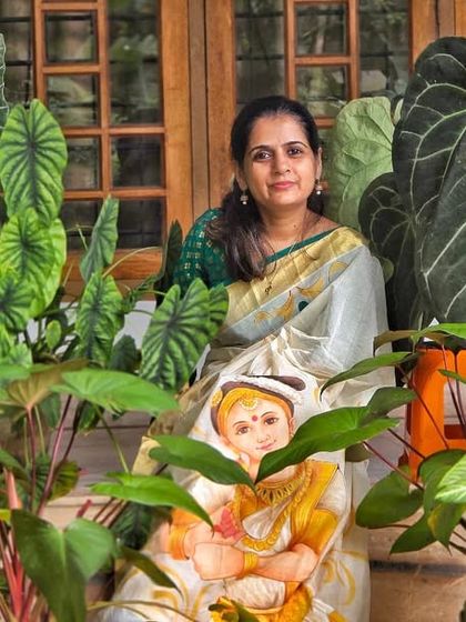 My wife sitting with her hand-painted saree that beautifully complements the exotic plants in our collection.