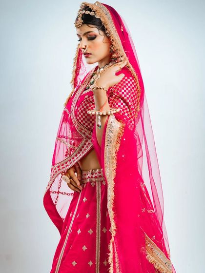A side profile showcasing the elegant drape of the dupatta and the detailed work on the blouse of this pink bridal lehenga.