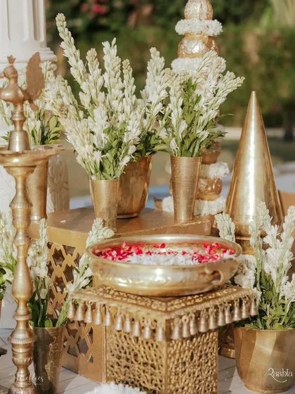 Traditional brass 'urlis' and vases filled with white tuberoses and floating petals, creating an auspicious and fragrant decor element.