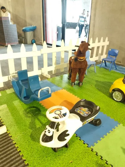 A variety of ride-on toys, including a rocking horse and a push car, set up on a soft play mat. I offer a range of toys to suit different toddler interests.