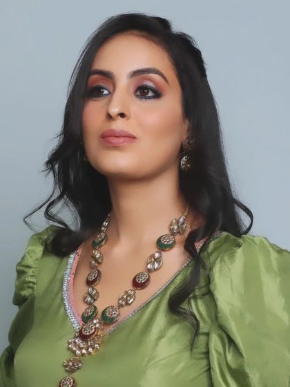 A full view of the soft glam engagement makeup. Her skin is glowing, and the eye makeup is subtle yet defined, which looks stunning with her traditional green and red jewelry.
