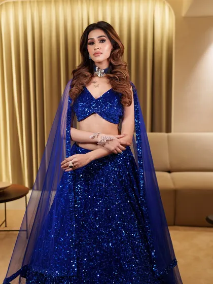 A super glam look featuring a royal blue sequin lehenga. The makeup is bold and dramatic, perfect for a bride who loves to sparkle.
