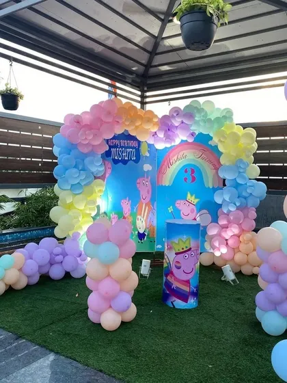 The main backdrop for the Peppa Pig party, featuring the characters, a rainbow, and a colorful pastel balloon arch.