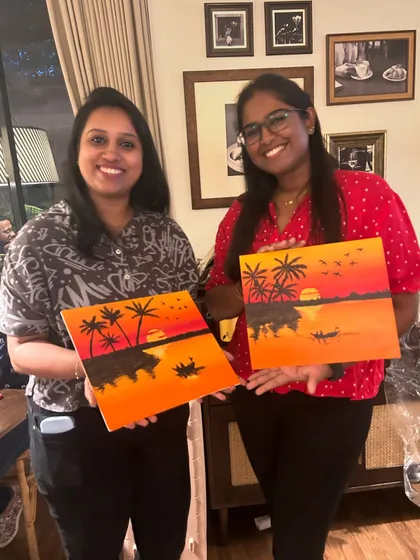 Two friends happily showing off their completed sunset silhouette paintings.
