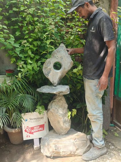 An artisan proudly stands beside the completed 4-foot abstract sculpture. Each piece is a result of immense passion and skill, transforming a block of stone into a work of art.