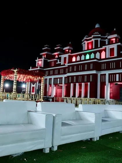 The royal palace facade illuminated at night, with comfortable white lounge seating arranged for guests on the lawn, combining grandeur with comfort.