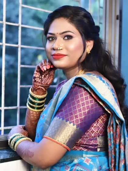The final look. This makeup features a soft, smokey eye and a classic red lip, perfectly complementing her blue and purple silk saree for a traditional yet fresh appearance.