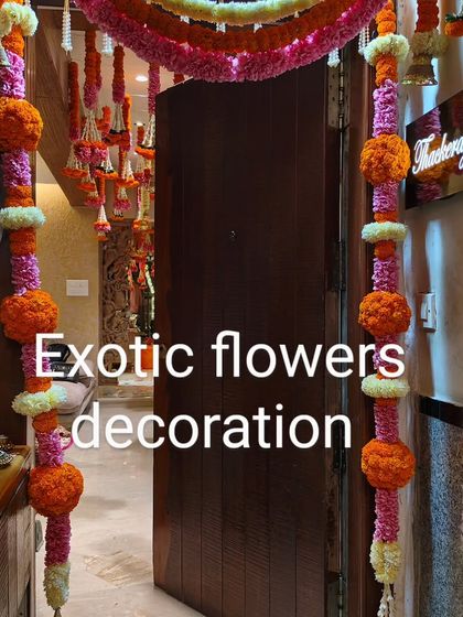 Traditional floral garlands in pink and orange adorn this home's entryway, creating a vibrant and festive passage into the celebration space.