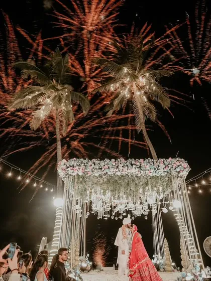 A destination wedding dream. The varmala on a beach stage, with palm trees and fireworks lighting up the night sky, is the definition of an epic celebration.