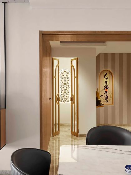 A view from the dining area looking towards the spiritual heart of the home. The open doors of the pooja room reveal the beautiful inlay work, integrating the sacred space seamlessly with the rest of the living area.