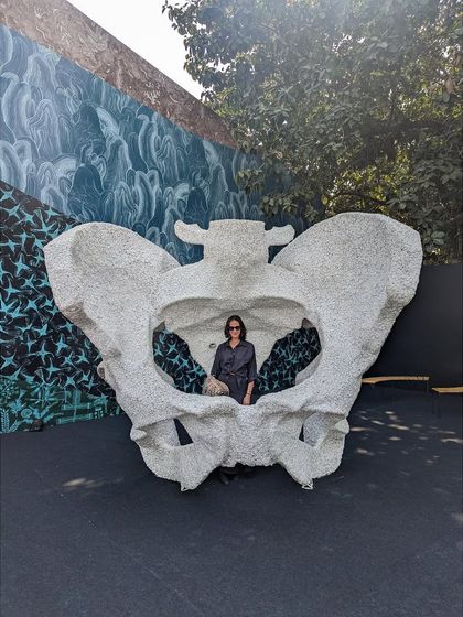 A visitor sitting inside the 'KAMA' sculpture. This demonstrates the scale and interactive nature of the work, which functions as both a monumental sculpture and a contemplative space.