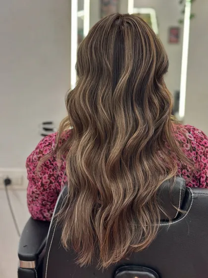 The final result of an Ash Blonde hair color service. The long, wavy hair has beautiful dimension and shine from the cool-toned highlights.