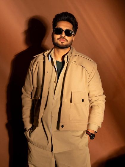 A medium shot that highlights the layers of his outfit and his confident pose.