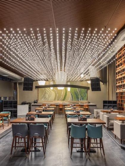 The main dining hall features a spectacular ceiling installation of countless points of light, creating a starlit canopy over the space.