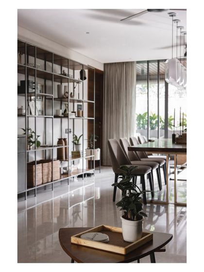 A floor-to-ceiling metal and glass shelving unit acts as a divider, providing ample display space for curios and mementos without closing off the dining area.