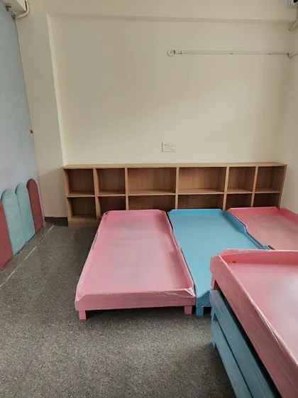 This is the designated nap room. We sourced these stackable, easy-to-clean cots and provided ample storage, creating a calm and organized space for children to rest.