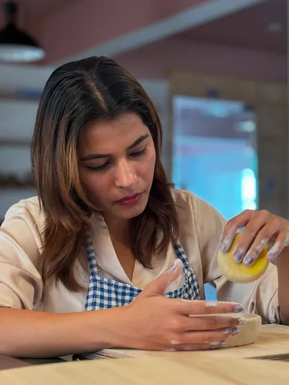 A student fully immersed in her craft, smoothing the surface of her hand-built piece.
