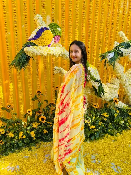 Posing against the stunning marigold decor at the Haldi ceremony. The vibrant yellow background made my outfit pop.