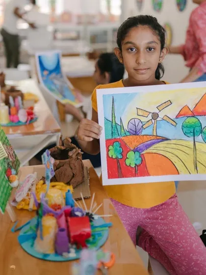 A proud moment captured at our camp's art show. This young lady created a beautiful and vibrant landscape using oil pastels, showcasing her new skills in blending and composition.