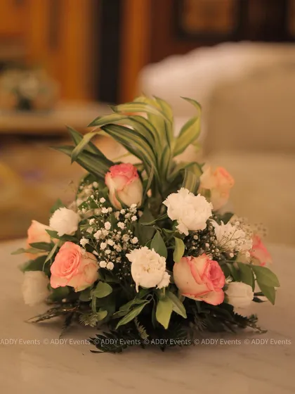 A classic and elegant low floral centerpiece with blush pink roses and white carnations. This type of arrangement is perfect for boardroom lunches, conference tables, or intimate corporate dinners.