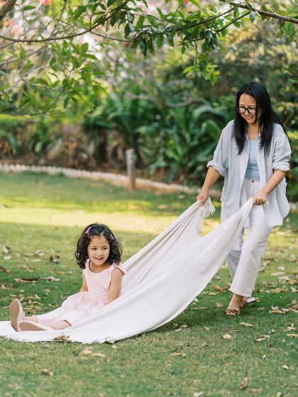 A mother pulling her daughter on a blanket, both laughing. Play is the best way to get genuine smiles from children.