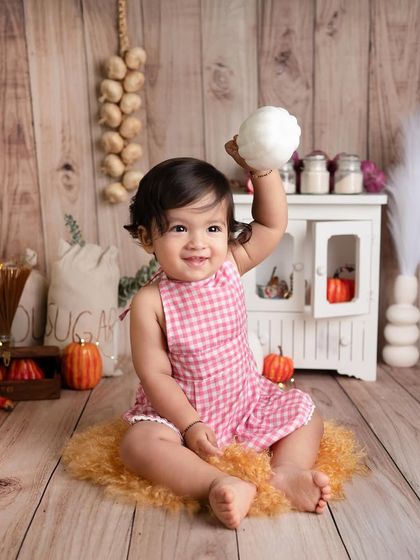 I just can't get enough of this little chef. Here she is, playing with a pumpkin in our rustic kitchen, looking absolutely adorable in her pink gingham apron.