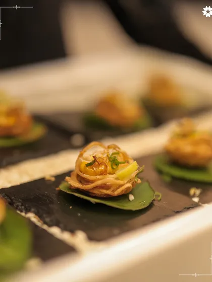 A crispy noodle basket appetiser, presented on a slate tile. The contrast of the delicate basket and the rustic slate highlights our focus on texture and presentation.