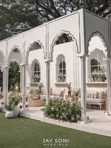 The full view of the stunning ivory lounge pavilion, an open-air structure that feels both grand and intimate, set on a lush green lawn.