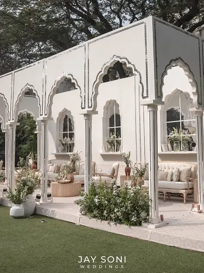 The full view of the stunning ivory lounge pavilion, an open-air structure that feels both grand and intimate, set on a lush green lawn.