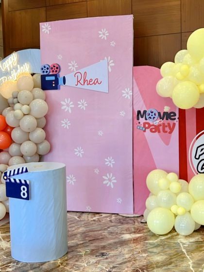 Lights, camera, action. Rhea's movie-themed party featured a fun popcorn box prop, a director's clapperboard, and a 'Happy Birthday' neon sign for a Hollywood-style celebration.