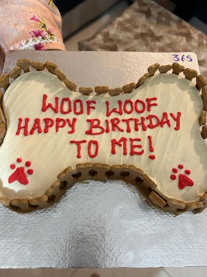 "Woof Woof Happy Birthday To Me!" This fun message is written on a classic bone-shaped cake, edged with crunchy baked biscuits.