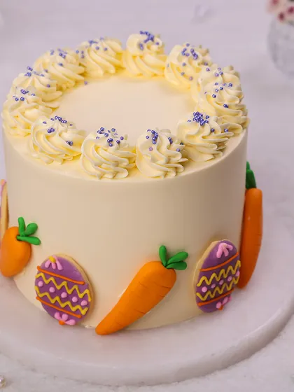 This simple yet beautiful Easter cake is topped with buttercream swirls and decorated with festive cookies.