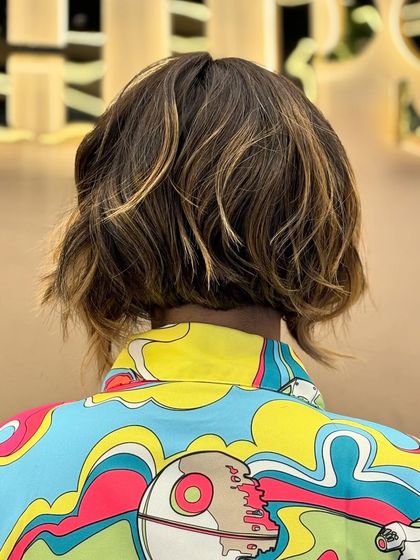 A back view of a wavy bob with fresh highlights. This look is playful and modern, with the color adding texture and dimension to the short style.